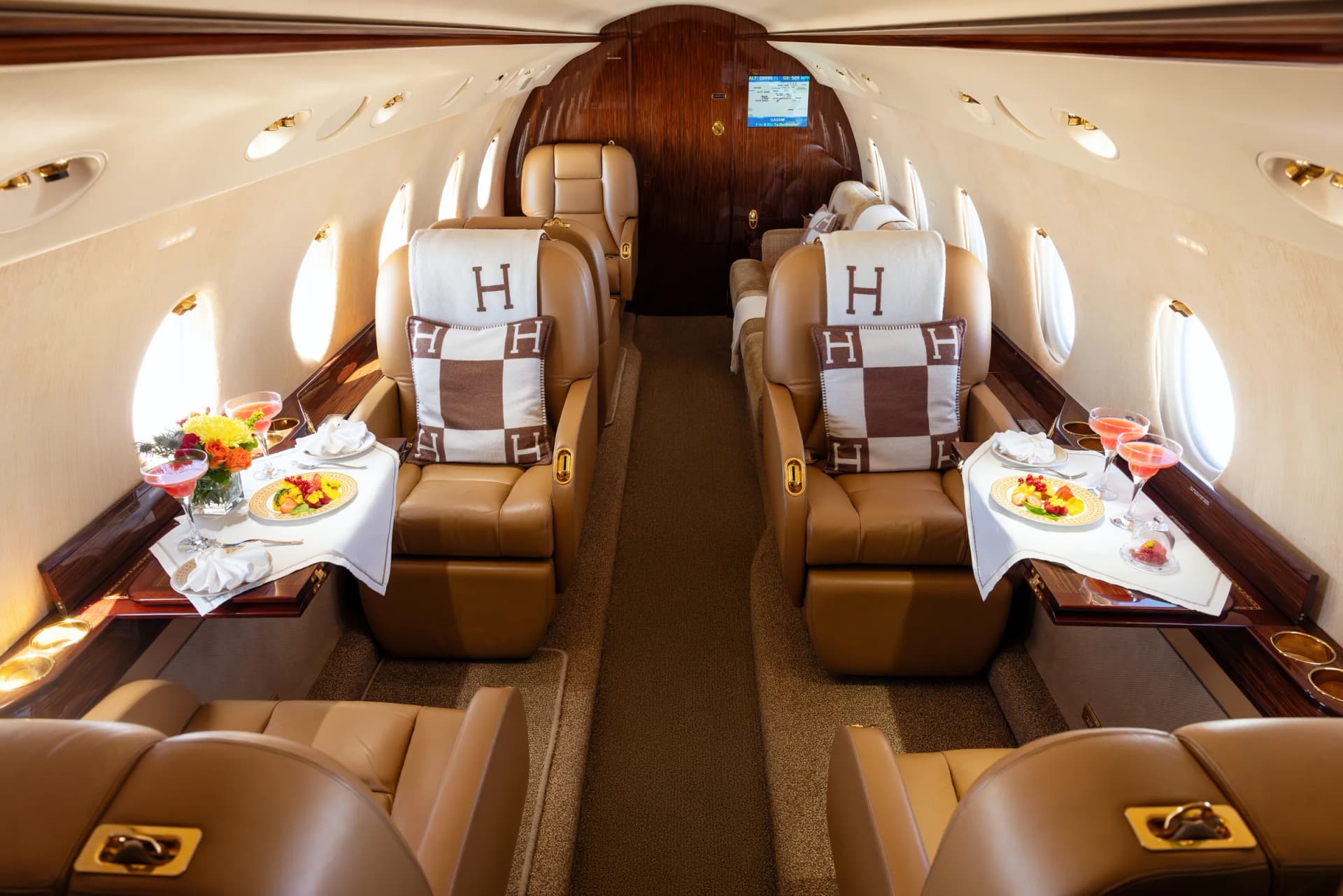 Gulfstream G200 club seats with Hermès cushions and tables set with flowers and fruit