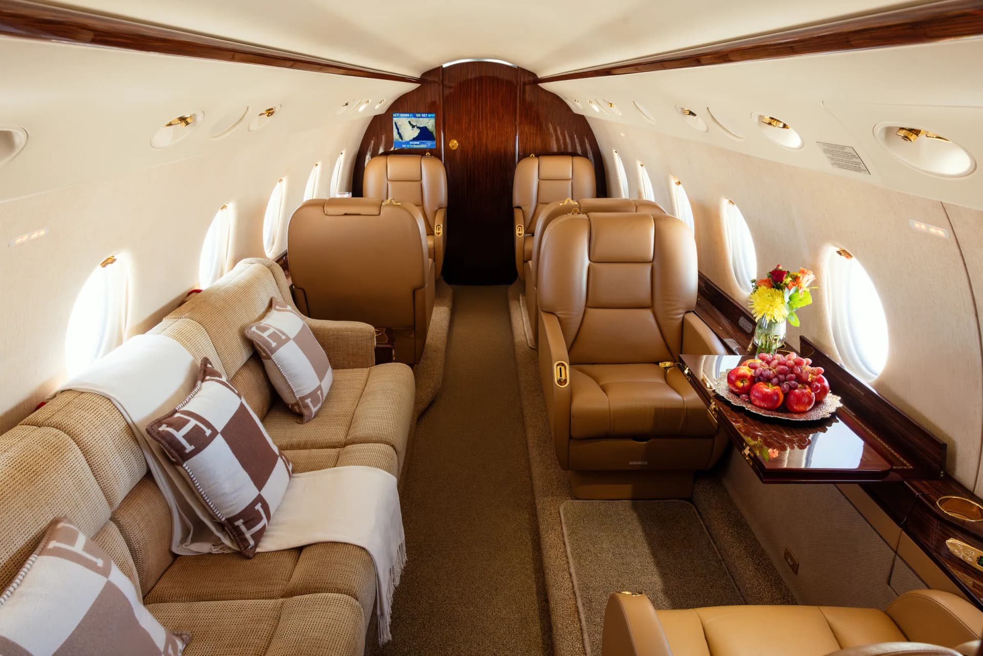 The Gulfstream G200 cabin with its divan, tan leather seats and a fruit platter on the side ledge