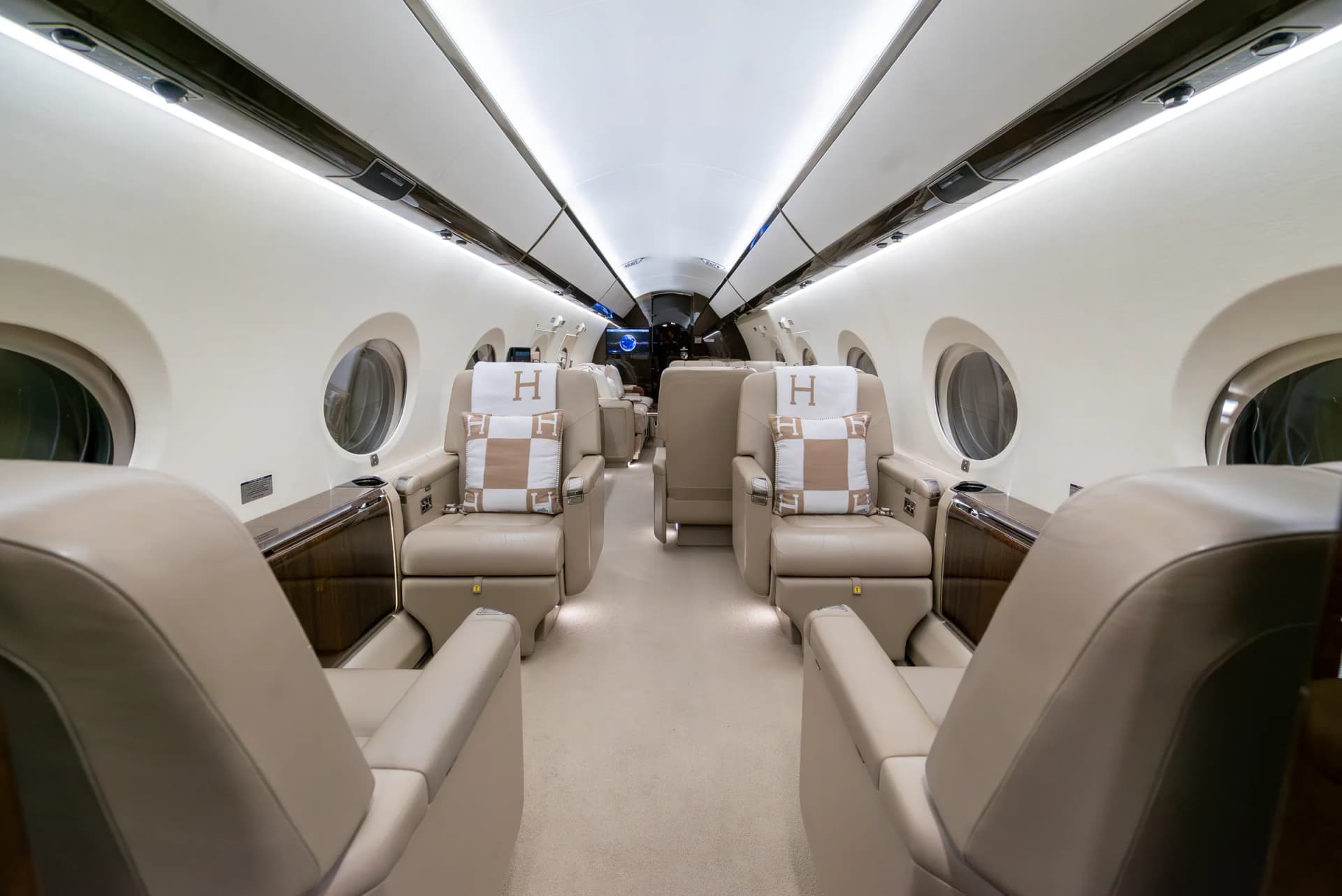 Gulfstream G450 cabin aisle between cream leather club seats with Hermès blankets and cushions