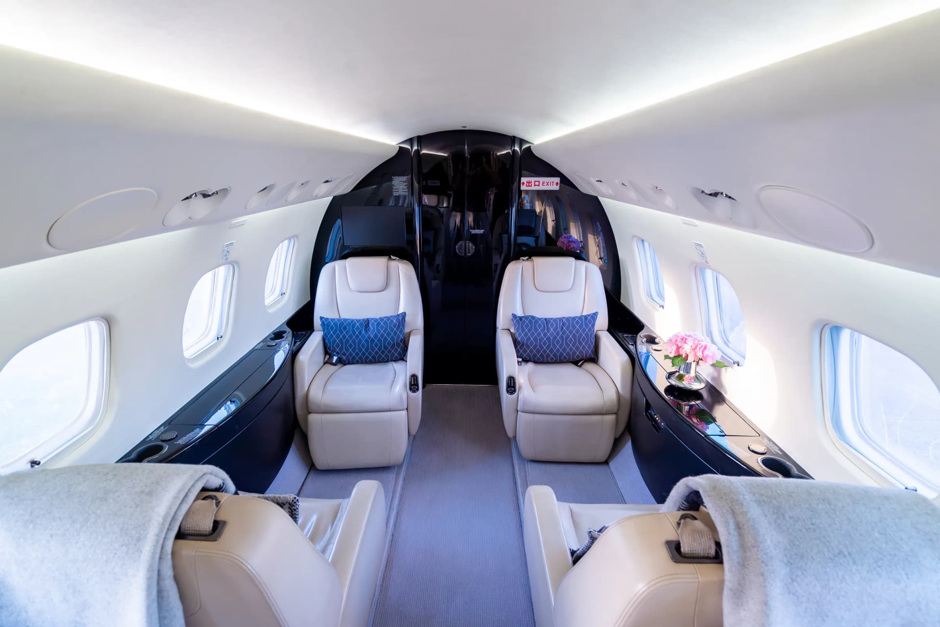 Cream club seats with blue cushions and soft blankets in the Embraer Legacy 650 cabin