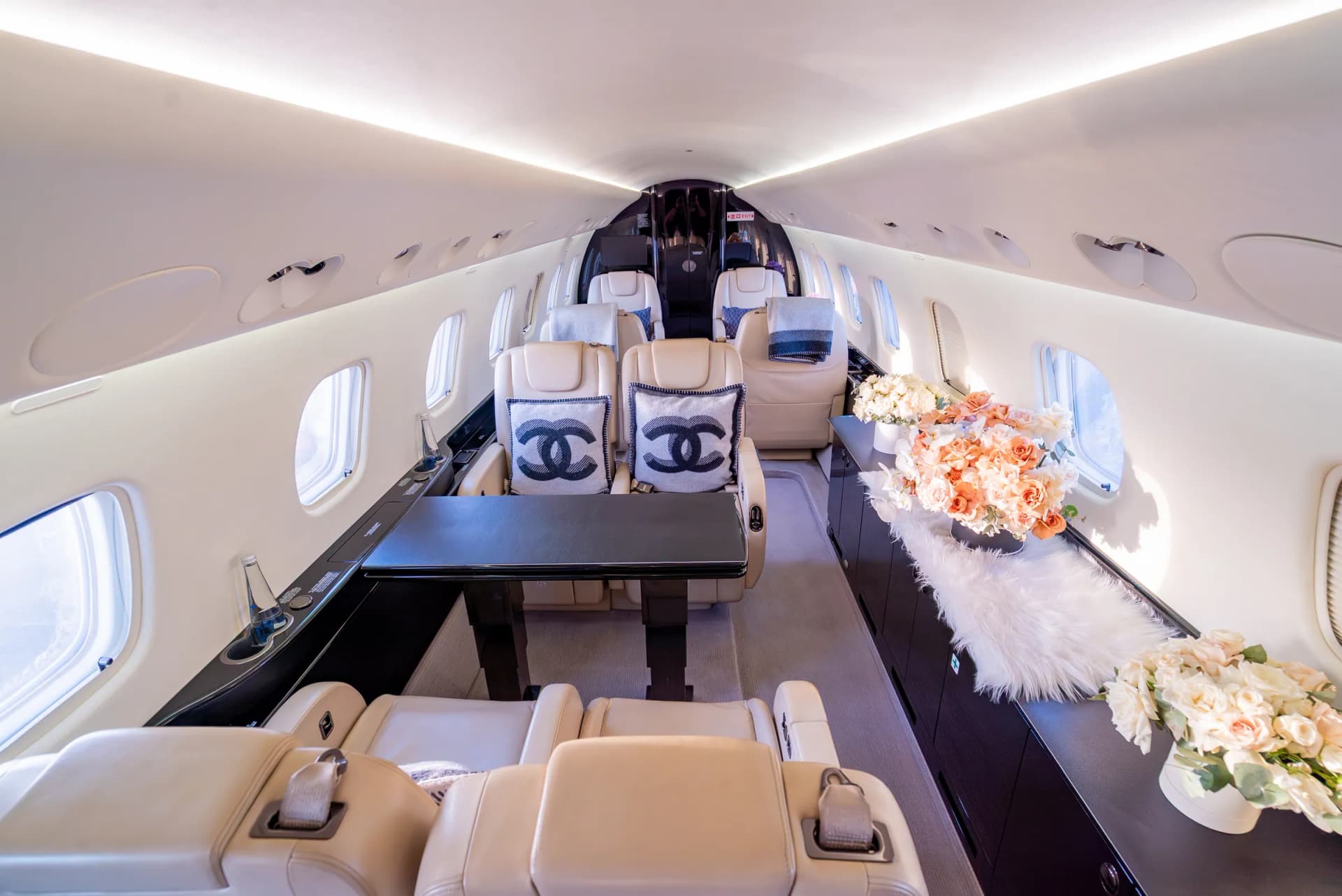 The Embraer Legacy 650 mid cabin, with the conference table and floral arrangements on the credenza