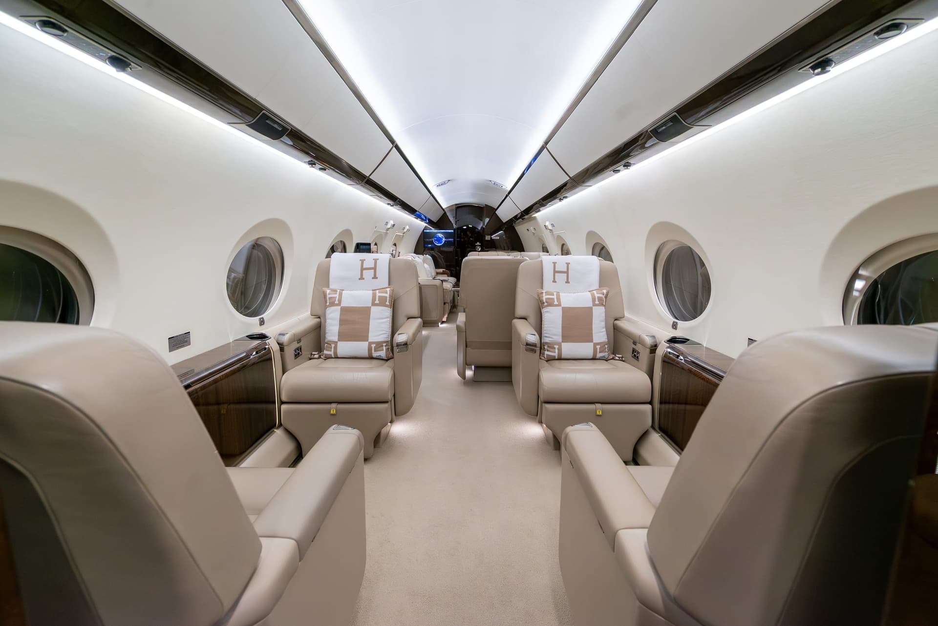 Gulfstream G450 cabin aisle between cream leather club seats with Hermès blankets and cushions