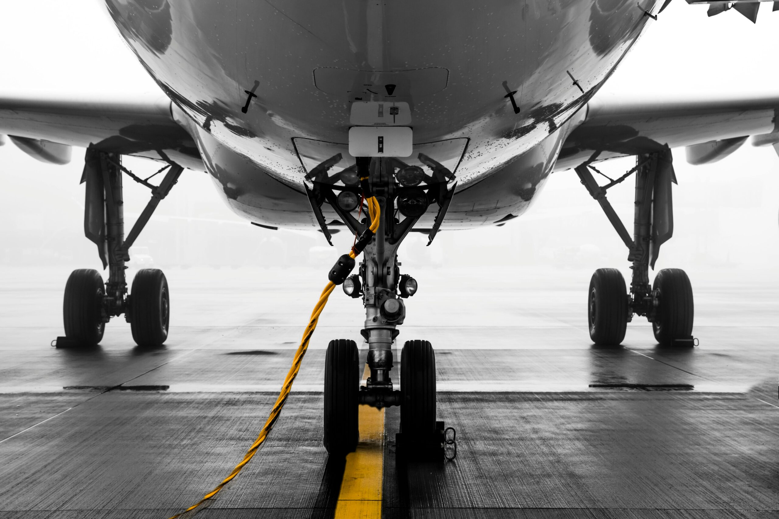 Close-up of a modern aircraft on a misty runway at Zürich Airport, highlighting the landing gear and foggy ambiance.